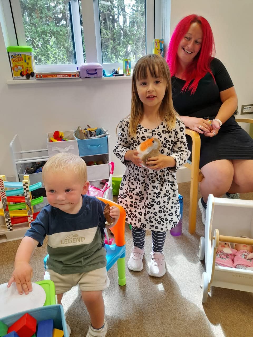 Sleeping toddler with blonde hair cuddling a blue stuffed animal under a pink blanket.